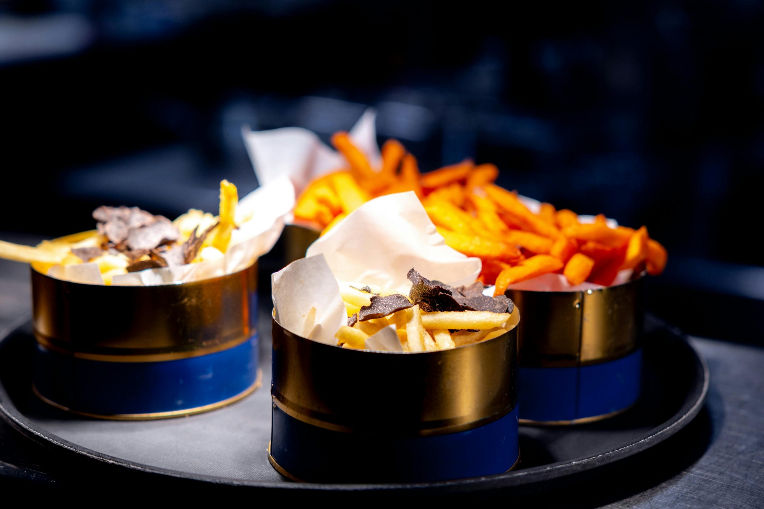 Elegant presentation of truffle and sweet potato fries in stylish tin cups, perfect for upscale dining.